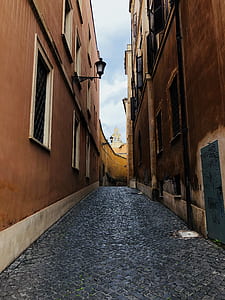pathway between concrete buildings under cloudy sky thumbnail