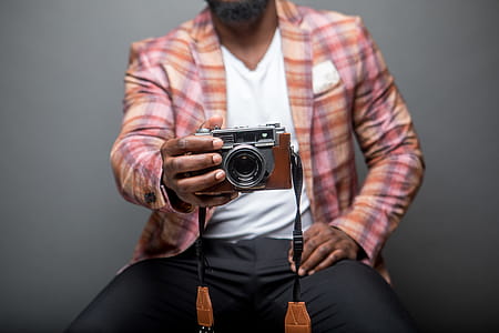 Selective Focus Photography of Man Sits While Holding Camera thumbnail