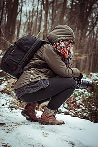 woman in brown jacket sitting near trees thumbnail