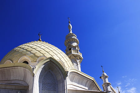 beige and white mosque building under blue skies thumbnail