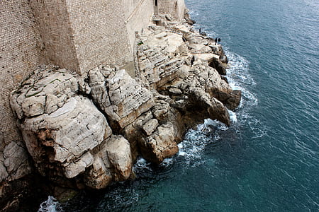 brown rock formation near body of water during daytime thumbnail