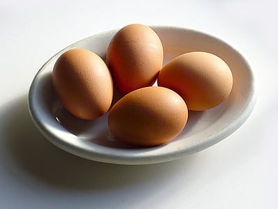 four brown eggs on white ceramic tray thumbnail