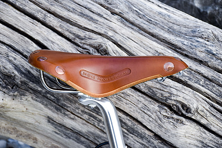 brown leather bicycle seat leaning at brown log thumbnail