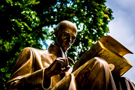 gold statue of man reading book thumbnail