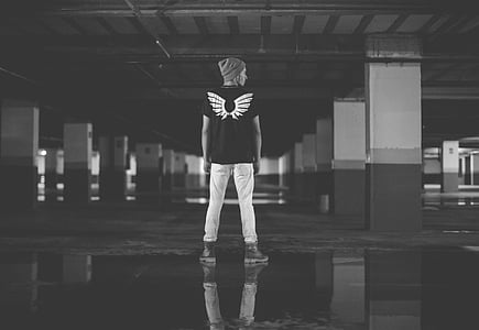 greyscale photo of man standing on concrete ground thumbnail