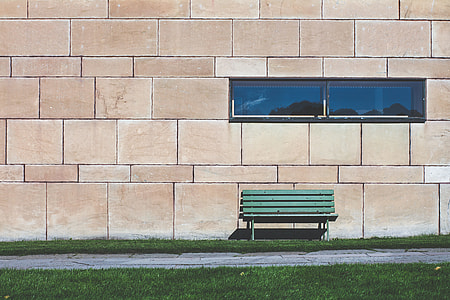 green park bench near beige wall thumbnail