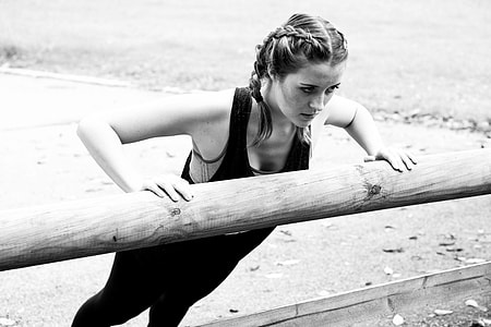 grayscale photo of woman wearing black shirt and pants doing push-up thumbnail