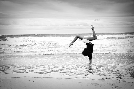grayscale photo of woman standing using hand on seashore thumbnail