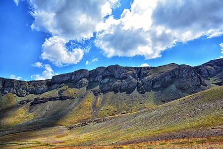 green grass field on mountain under white clouds and blue sky at daytime thumbnail