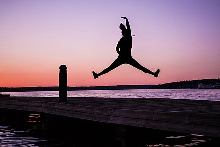 Silhouette of woman jumping on the coast at sunset thumbnail