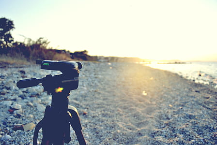 black tripod on sands near body of water thumbnail