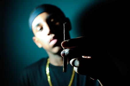 man holding brown cigarette stick thumbnail