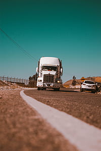 white freight truck beside white SUV on road thumbnail