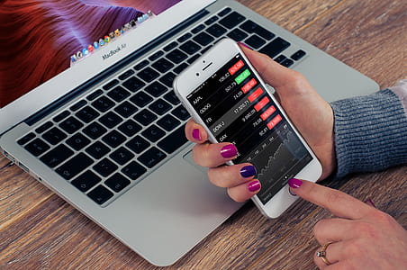 person holding turned on iPhone in front of turned on MacBook Air thumbnail
