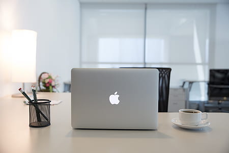 silver MacBook on white desk near teacup filled with coffee thumbnail