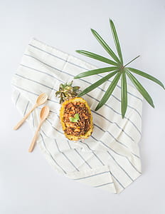 flat-lay photography of sliced pineapple, leaf, two spatulas on blanket thumbnail