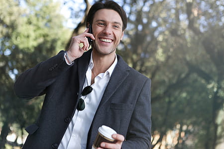 A young caucasian man in grey coat calling on his mobile phone outdoors thumbnail