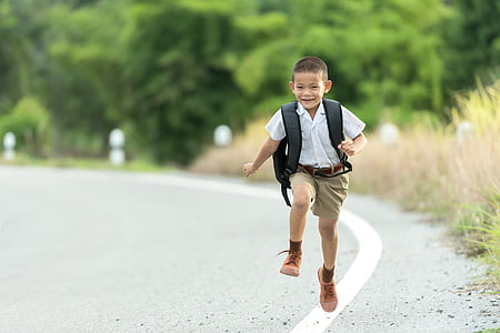 boy carrying backpack walking on road thumbnail