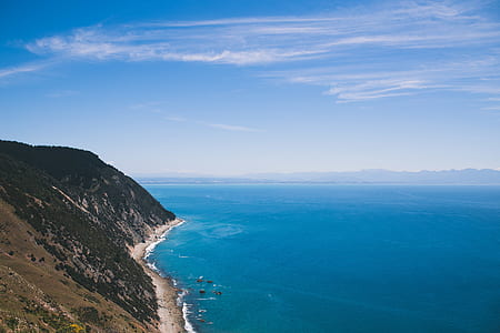 aerial photography of body of water beside mountain thumbnail
