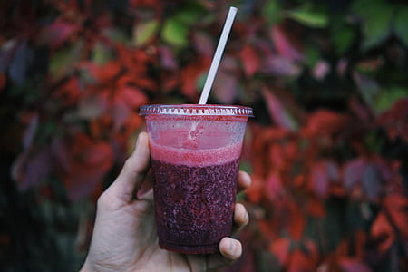person holding clear plastic cup with red liquid thumbnail