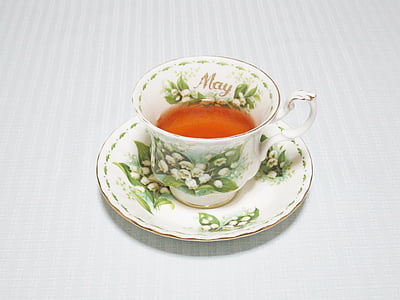 white and green floral teacup filled with brown liquid on saucer thumbnail