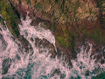 body of water splashing through brown and green cliff thumbnail