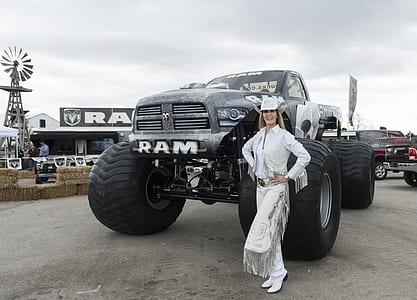 smiling woman standing in front of black Dodge Ram 1500 single cab pickup truck at daytime thumbnail