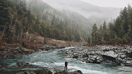 person standing on stone near river thumbnail