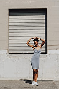 woman wearing spaghetti strap dress standing behind shutter door thumbnail