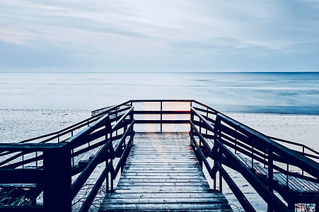 brown wooden dock through body of water during daytime thumbnail