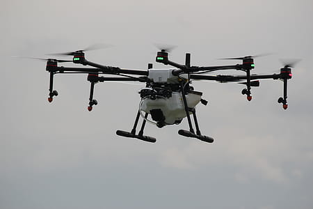 flying white and black drone under clouded sky thumbnail
