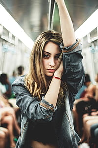 selective focus photography of woman resting head on her left arm while holding on horizontal pole thumbnail