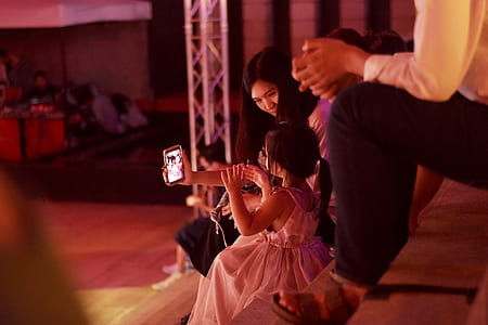 photo of woman holding smartphone and taking a photo of girl thumbnail