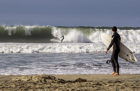 person standing beside seashore holding surfboard thumbnail