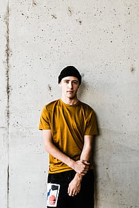 man in yellow shirt standing against the wall thumbnail