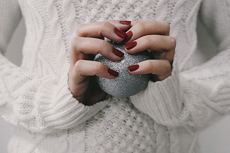 Closeup shot of a woman’s hands holding a silver Christmas decoration ball thumbnail