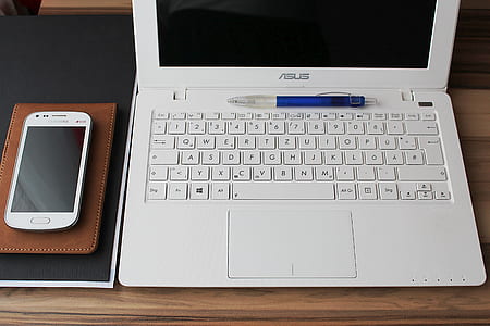 white Samsung smartphone beside white Asus laptop thumbnail