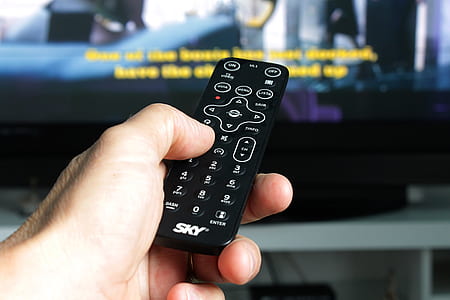 selective focus photography of person holding remote near television thumbnail
