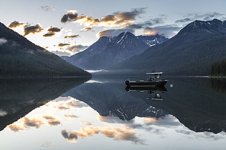 brown boat on large body of water surrounded by mountains during daytime thumbnail