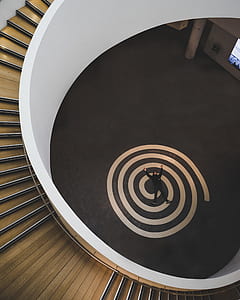 man lying on round mark near spiral wooden stairs thumbnail