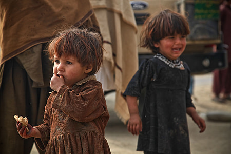 two toddler girls in brown and blue dresses while  eating and crying during daytime thumbnail