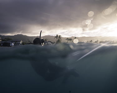 man swimming on body of water thumbnail