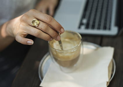 person holding spoon on clear drinking glass thumbnail
