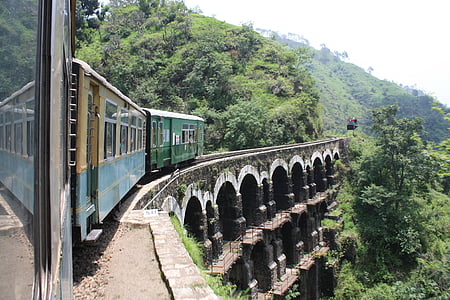 green train passing on brown arch bridge thumbnail