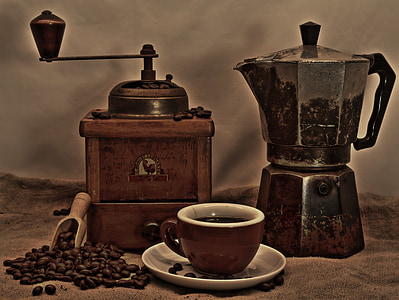 brown manual coffee grinder and black and brown coffee pot behind brown and white ceramic coffee cup thumbnail