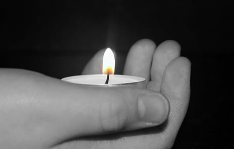 grayscale photo of person's hand holding tealight candle thumbnail