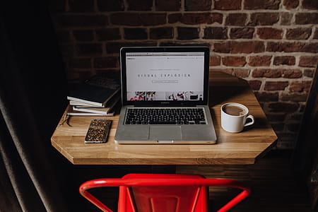 Creatives desk with laptop, camera, journals and books in front of brick wall thumbnail