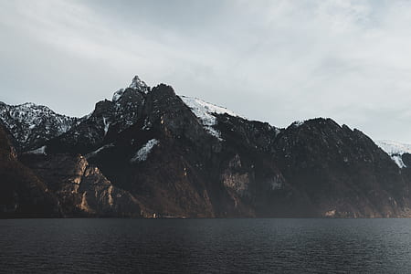 photo of body of water near mountains covered with snow thumbnail