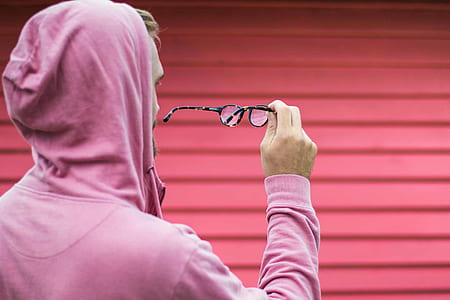 person wearing pink hoodie holding black framed eyeglasses thumbnail