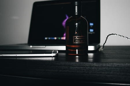 glass bottle beside laptop computer thumbnail